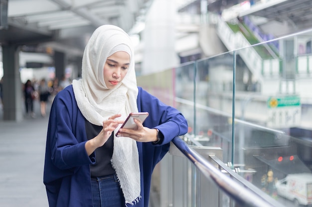 Giovane donna musulmana che per mezzo dello smartphone.