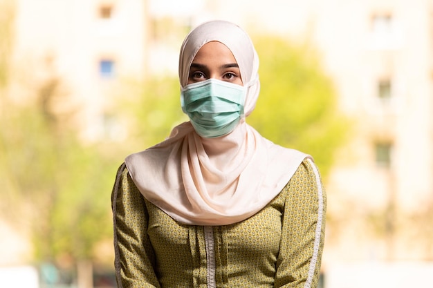 Giovane donna musulmana che prega in moschea con maschera chirurgica e guanti