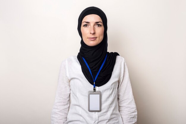 Giovane donna musulmana in camicia bianca e hijab con badge ufficio