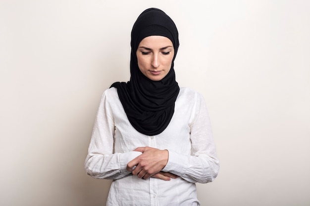 Giovane donna musulmana vestita con una camicia bianca e pregando hijab