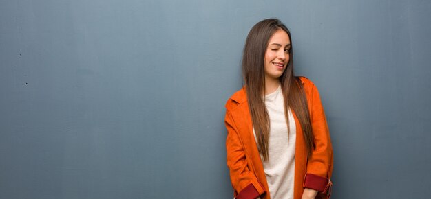 Giovane donna naturale che sbatte le palpebre, gesto divertente, amichevole e spensierato