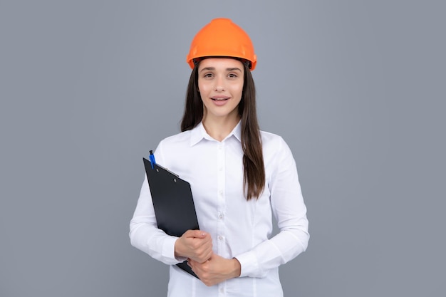 Giovane donna nel casco elmetto con appunti isolato su sfondo grigio Donna architetto indossare il casco e la camicia Costruttore di manager di costruzione donna d'affari