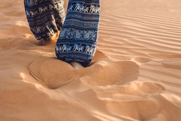 Giovane donna nel deserto sabbioso al tramonto o all'alba