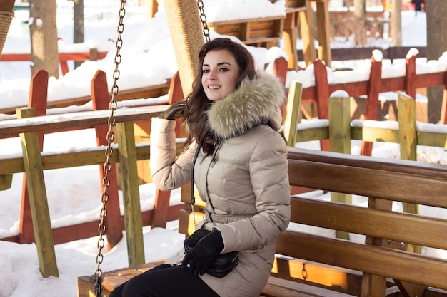 Giovane donna nel parco invernale seduto su una panchina con molta neve intorno