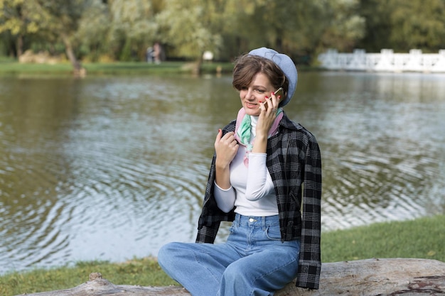 Giovane donna nel parco parla con il cellulare Ritratto di ragazza carina in stile francese