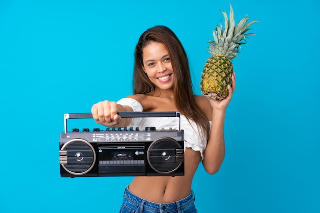 Giovane donna nelle vacanze estive che tiene una radio e un ananas