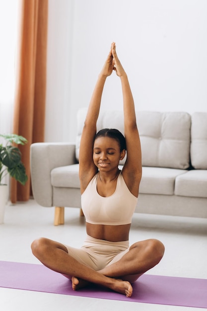 Giovane donna nera che medita a casa, concetto di yoga online, spazio libero