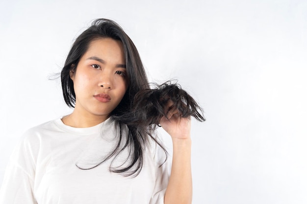 Giovane donna nera con i capelli disordinati su uno sfondo bianco Le donne asiatiche sono preoccupate per i loro capelli danneggiati che causano una mancanza di fiducia