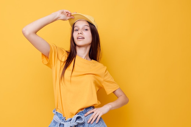 Giovane donna ottimista che posa in una maglietta gialla e in una priorità bassa gialla del cappuccio