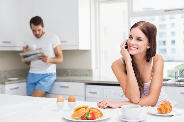 Giovane donna parla al telefono a colazione