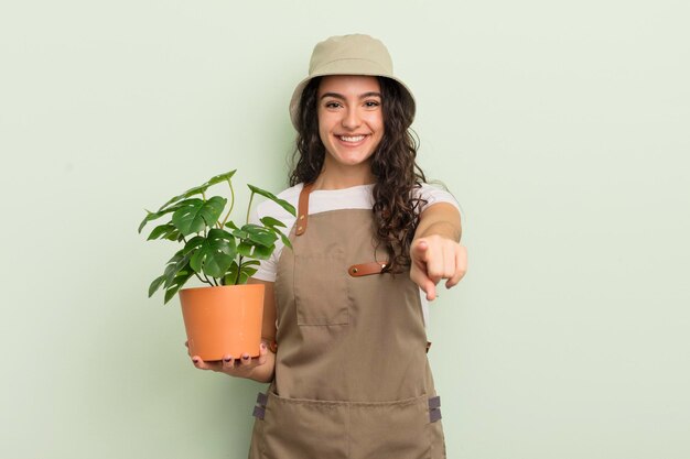 Giovane donna piuttosto ispanica che punta alla telecamera scegliendo il concetto di agricoltore o giardiniere