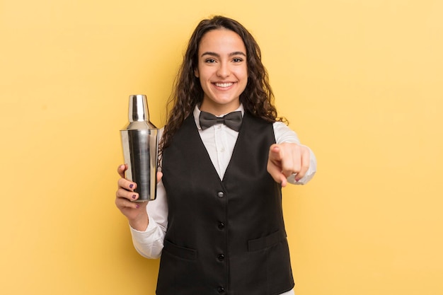 Giovane donna piuttosto ispanica che punta alla telecamera scegliendo il concetto di barista e cocktail