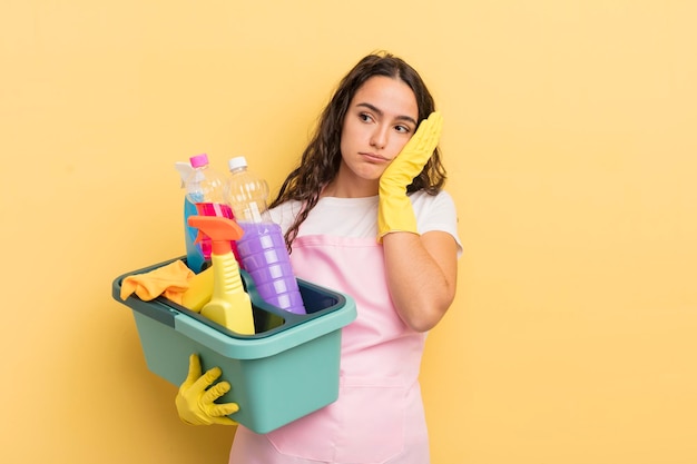 Giovane donna piuttosto ispanica che si sente annoiata, frustrata e assonnata dopo un noioso lavoro domestico e un concetto di prodotti puliti