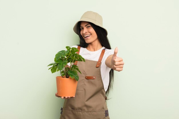 Giovane donna piuttosto ispanica che si sente orgogliosa di sorridere positivamente con il pollice in alto concetto di agricoltore o giardiniere