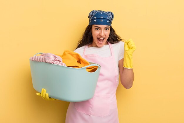 Giovane donna piuttosto ispanica che si sente scioccata ridendo e celebrando il successo del lavaggio e del concetto di vestiti