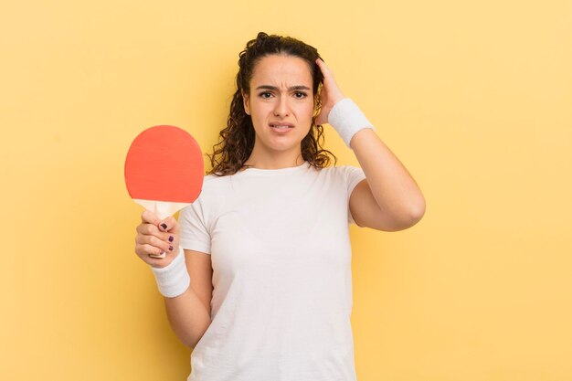 Giovane donna piuttosto ispanica che si sente stressata o spaventata con le mani sul concetto di ping pong testa