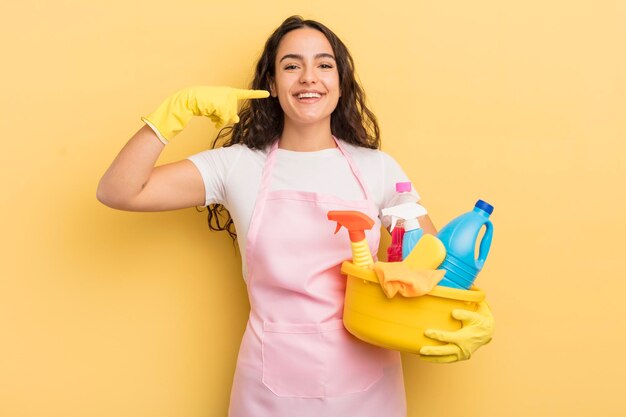 Giovane donna piuttosto ispanica che sorride con sicurezza indicando di possedere un ampio sorriso lavori domestici un concetto di prodotti puliti