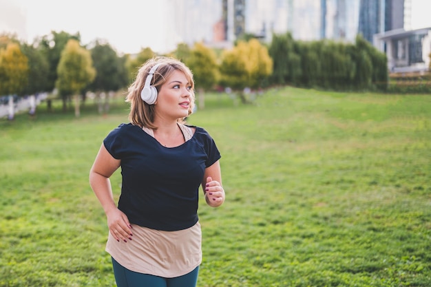 Giovane donna plus size che corre in un parco cittadino sano e stile di vita fitness concetto positivo per il corpo