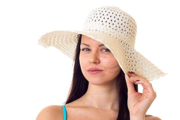 Giovane donna positiva con lunghi capelli scuri in costume da bagno blu con cappello bianco in studio