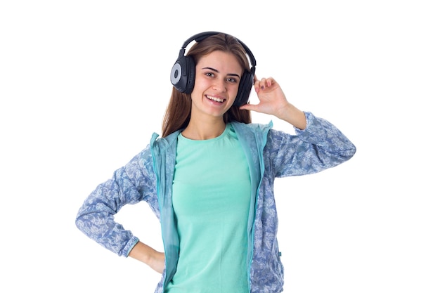 Giovane donna positiva in camicia blu che ascolta la musica in cuffie nere in studio