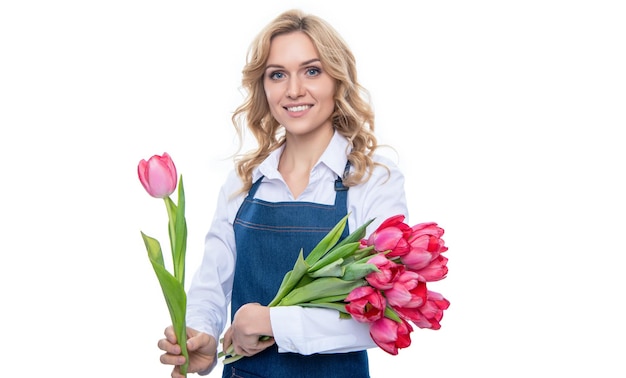 Giovane donna positiva in grembiule con fiori di tulipano primaverili isolati su sfondo bianco