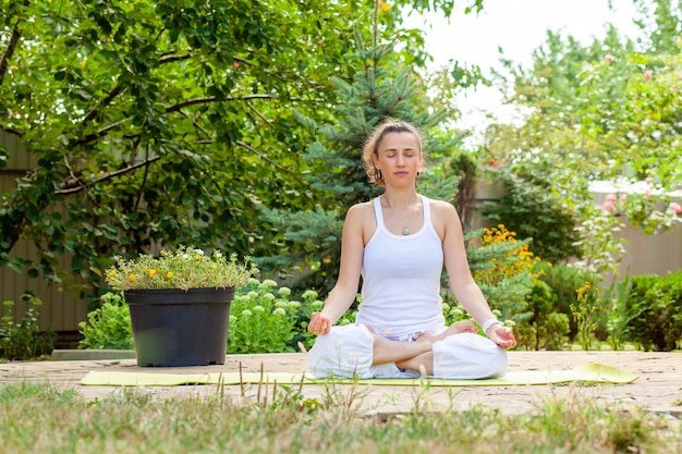 Giovane donna pratica yoga in giardino