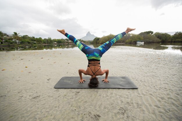 Giovane donna pratica yoga sulle rive dell'Oceano Indiano