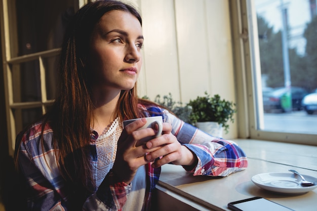 Giovane donna premurosa che mangia caffè al caffè