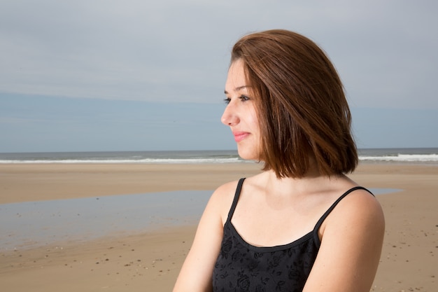 Giovane donna premurosa che osserva via con il mare sullo sfondo