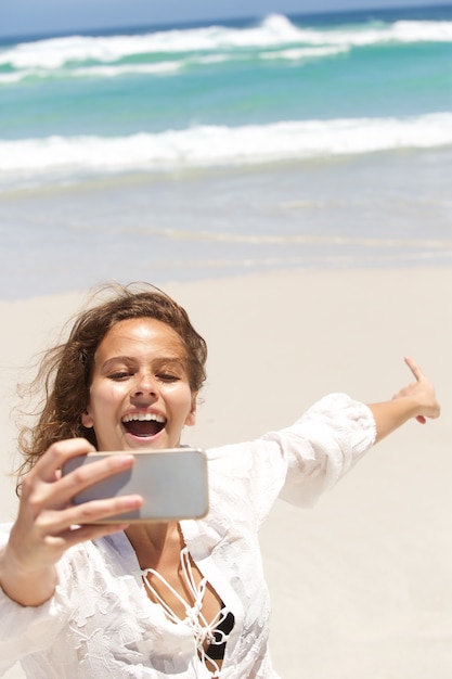 Giovane donna prendendo selfie e indicando il mare
