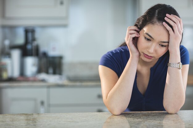 Giovane donna preoccupata che si siede nella cucina