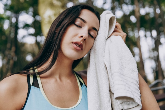 Giovane donna pulisce il viso con un asciugamano dopo l&#39;allenamento