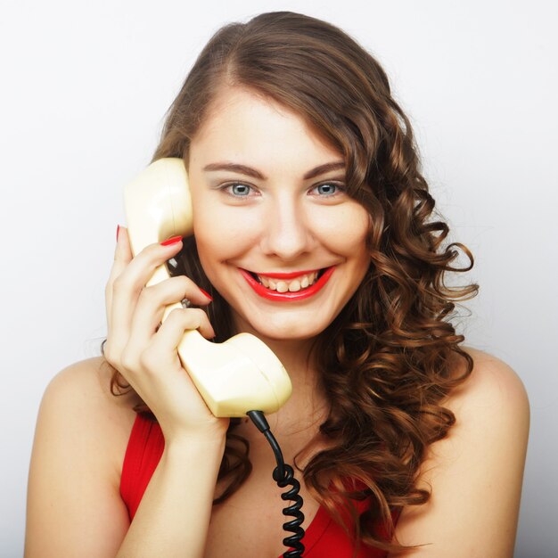 Giovane donna riccia con telefono vintage.