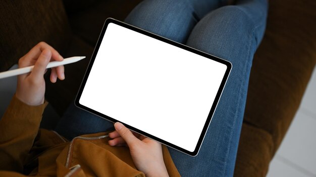 Giovane donna rilassata che utilizza il touchpad della tavoletta digitale sul suo divano moderno e confortevole a casa