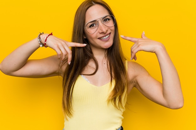 Giovane donna rossa dello zenzero con sorrisi freckless, puntando le dita alla bocca.