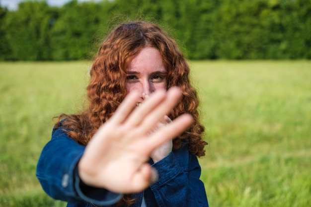 Giovane donna rossa timida prima della fotografia che copre la fotocamera