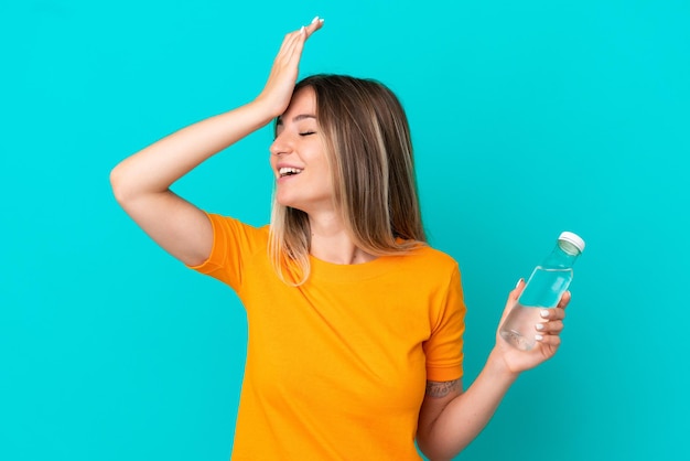 Giovane donna rumena con una bottiglia d'acqua isolata su sfondo blu che sorride molto