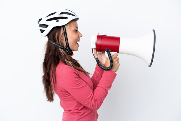 Giovane donna russa che indossa un casco da bici isolato su sfondo bianco che grida attraverso un megafono