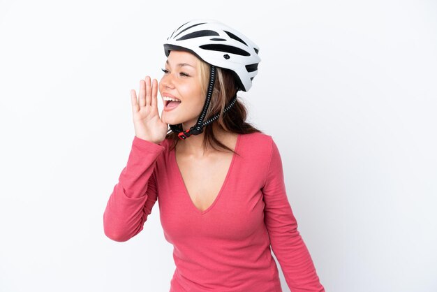 Giovane donna russa che indossa un casco da bici isolato su sfondo bianco che grida con la bocca spalancata lateralmente