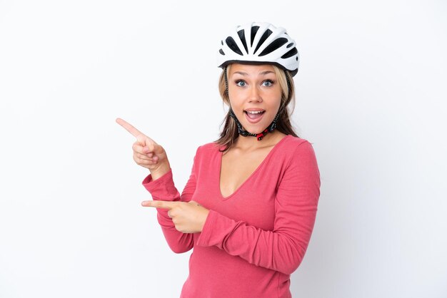 Giovane donna russa che indossa un casco da bici isolato su sfondo bianco sorpreso e rivolto verso il lato