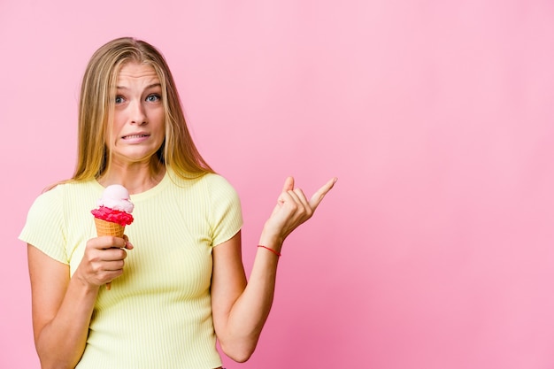 Giovane donna russa che mangia un gelato isolato scioccato che punta con le dita indice a uno spazio di copia.