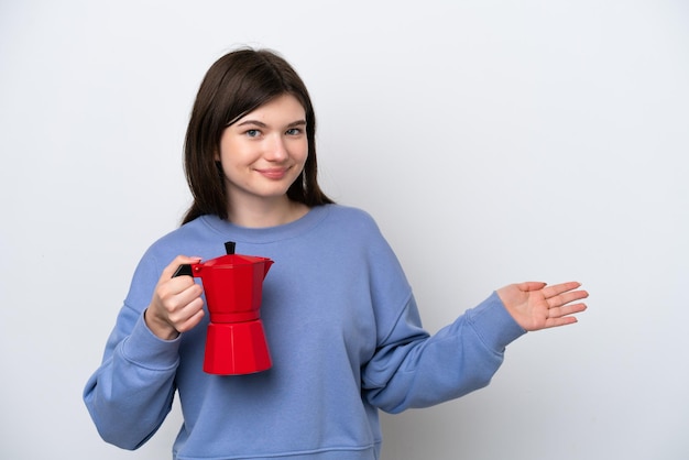 Giovane donna russa che tiene caffettiera isolata su sfondo bianco estendendo le mani di lato per invitare a venire