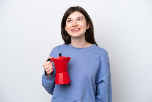 Giovane donna russa che tiene caffettiera isolata su sfondo bianco pensando a un'idea mentre alza lo sguardo