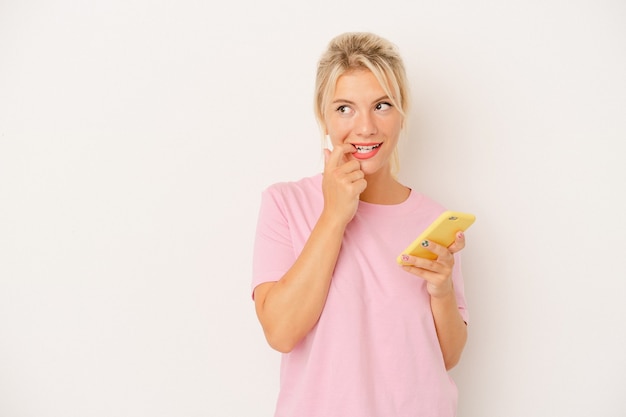 Giovane donna russa che tiene il telefono cellulare isolato su sfondo bianco rilassato pensando a qualcosa guardando uno spazio di copia.