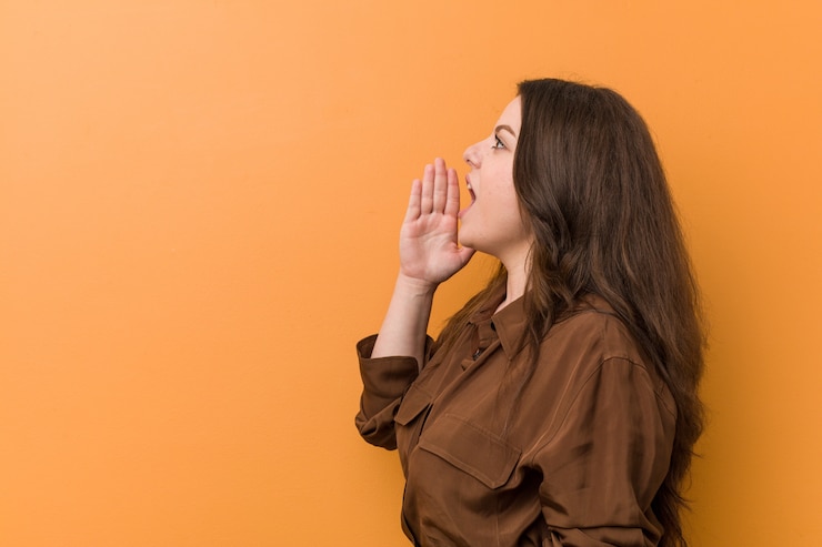 Foto giovane donna russa curvy che grida e che tiene la bocca aperta vicina della palma.