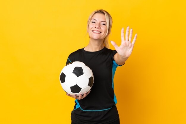 Giovane donna russa del giocatore di football americano isolata sul giallo che conta cinque con le dita