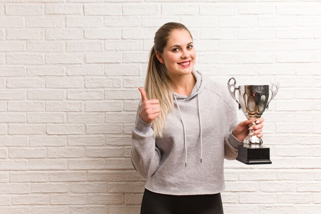 Giovane donna russa di forma fisica che tiene un trofeo