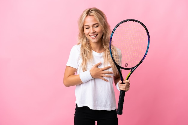 Giovane donna russa giocando a tennis isolato su sfondo viola sorridente molto