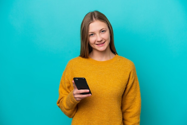 Giovane donna russa isolata su sfondo blu tramite telefono cellulare