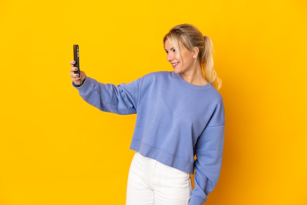 Giovane donna russa isolata su sfondo giallo facendo un selfie
